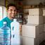 Saulo Starp junto a cajas de agua en un pequeño negocio